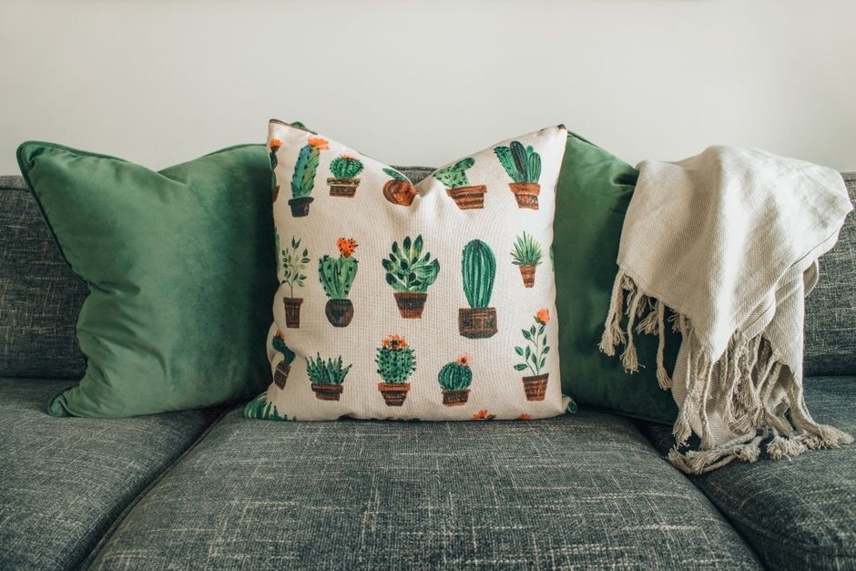 Gestyled bed met groene sierkussens en dekens.